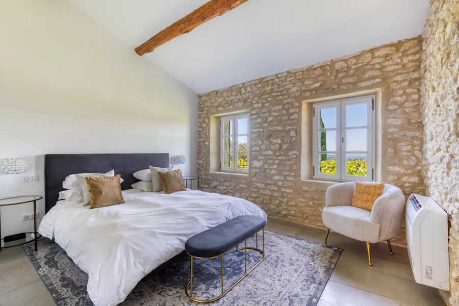 A bedroom with an exposed stone wall